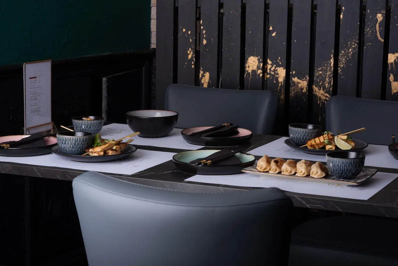 Hou Hou Mei restaurant interior table setting with Asian cuisine dishes and gold-accented dark decor