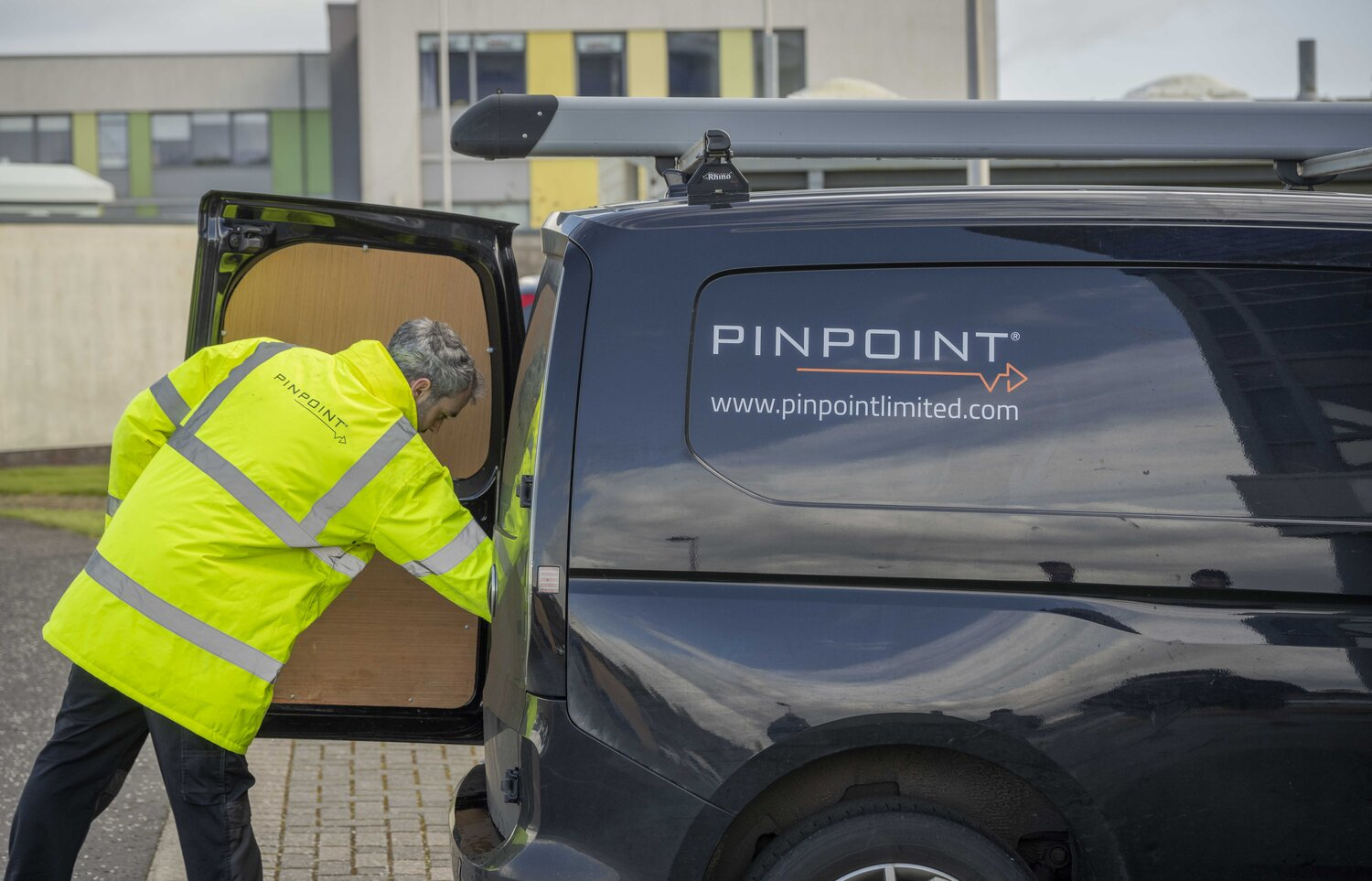 Pinpoint Ltd engineer in high-visibility jacket loading equipment into branded company van