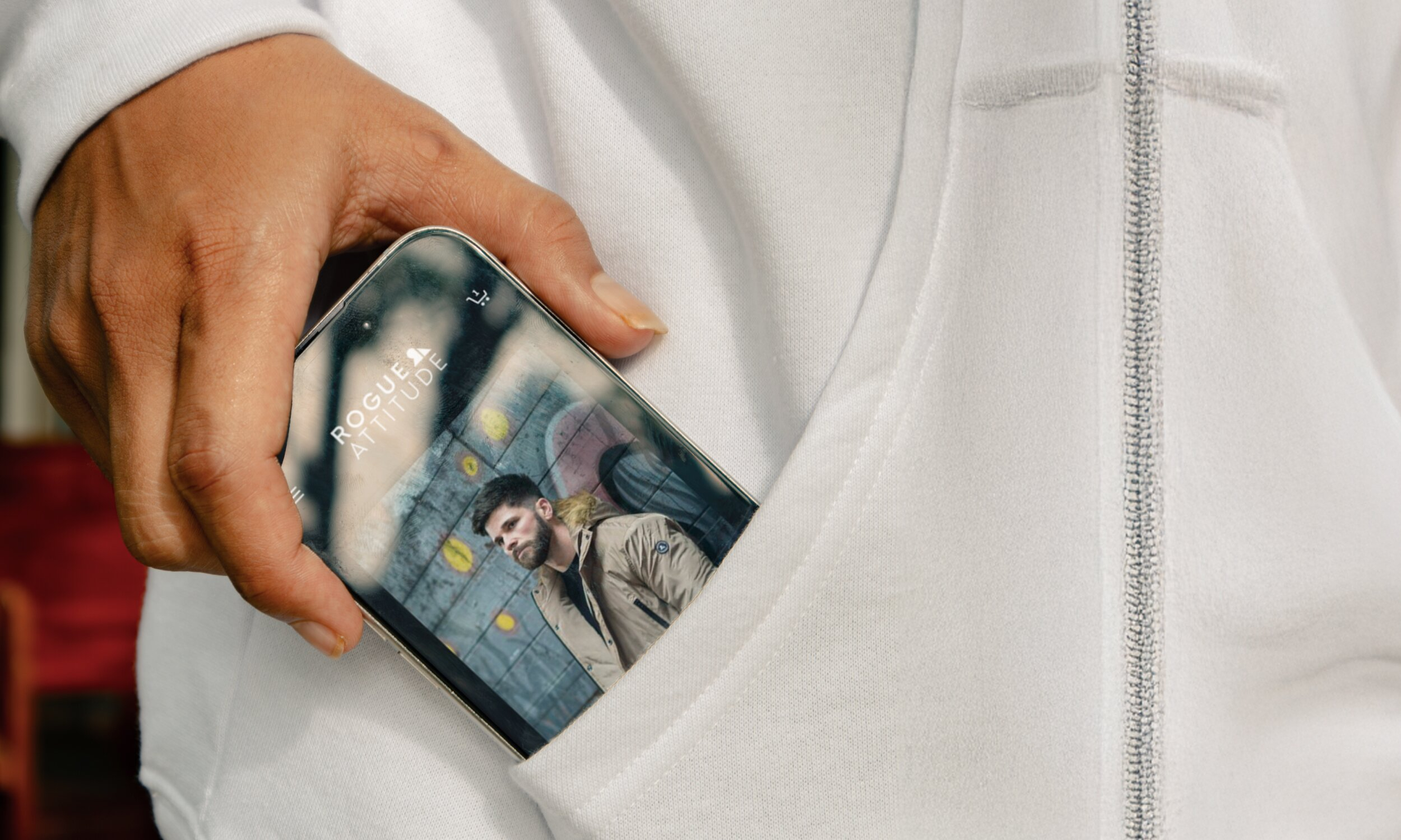 Hand holding smartphone displaying Rogue Attitude brand imagery on screen